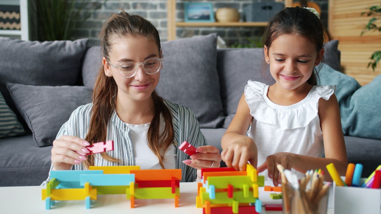 A mother and daughter engaging in play with vibrant building blocks at home.